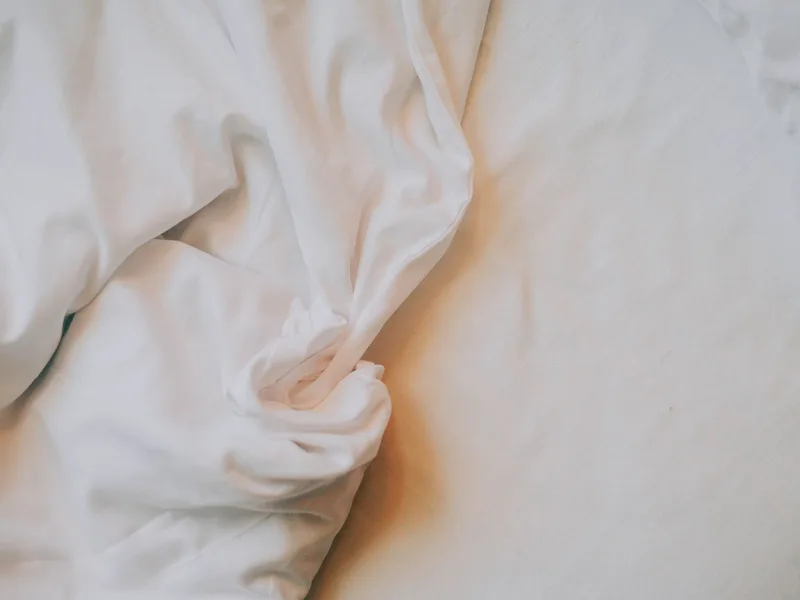 ملاءة بيضاء مجعّدة على سرير
